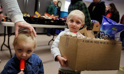 Two children at a food distribution event, one holding a box of snacks and the other with a — US poverty rate census data