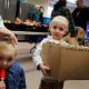 Two children at a food distribution event, one holding a box of snacks and the other with a — US poverty rate census data
