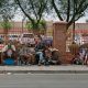 People sitting along sidewalk beside red fence — Escambia County homelessness laws