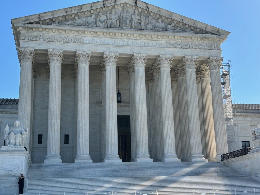 The U.S. Supreme Court building with its iconic columns and steps, under a clear blue sky. — Supreme Court mail voting rule