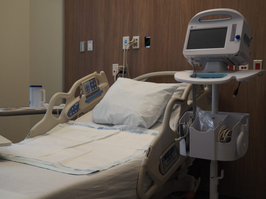 Empty hospital bed in a medical room with monitoring equipment nearby, reflecting hea — Medicaid work requirements lawsuit
