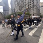 A procession of bagpipers and drummers in uniform marching down a city street, honor — 25th anniversary of Sept 11 attacks