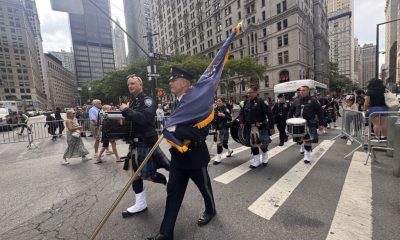 A procession of bagpipers and drummers in uniform marching down a city street, honor — 25th anniversary of Sept 11 attacks