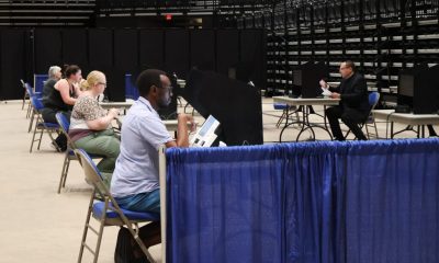 Voters casting their ballots in a spacious indoor polling location, with social d — noncitizen voting supreme court ruling