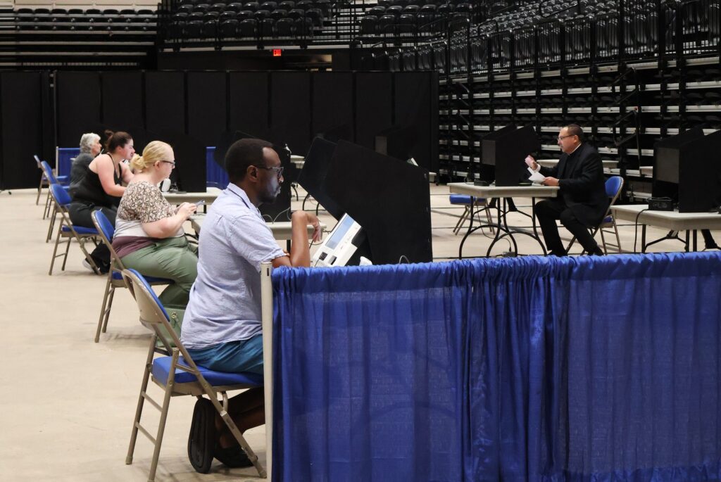 Voters casting their ballots in a spacious indoor polling location, with social d — noncitizen voting supreme court ruling