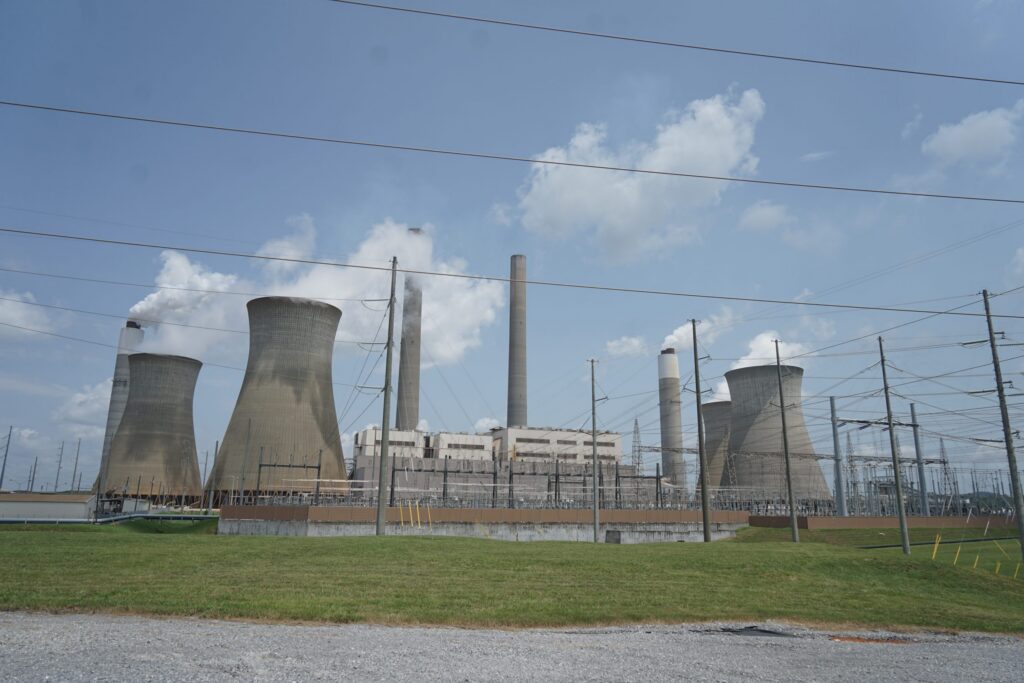Coal and natural gas power plant with cooling towers and power lines under a cloudy sky, — Trump EPA power plant emissions
