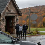 Two police officers escort a woman outside a stone building in Bennington, VT, with autumn — Sadie Mae Olden Bennington VT