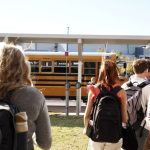 Students walking towards a yellow school bus on a sunny day, highlighting school safety measures. — school panic alarms