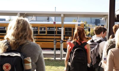 Students walking towards a yellow school bus on a sunny day, highlighting school safety measures. — school panic alarms