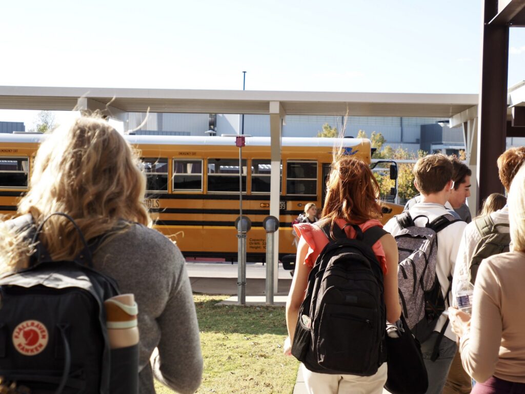 Students walking towards a yellow school bus on a sunny day, highlighting school safety measures. — school panic alarms