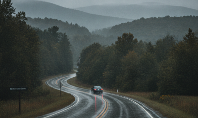 A winding road in Bennington County under rainy, overcast skies, with a car driving through pu — Bennington County weather
