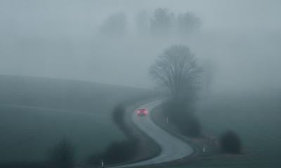 A winding road through a foggy landscape with a red car visible in the distance, illustratin — dense fog Bennington County