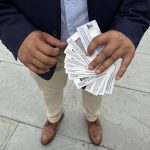 A person holding multiple identification cards in their hands, standing on a stone surface. — TPS El Salvador Expiration