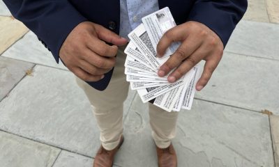 A person holding multiple identification cards in their hands, standing on a stone surface. — TPS El Salvador Expiration