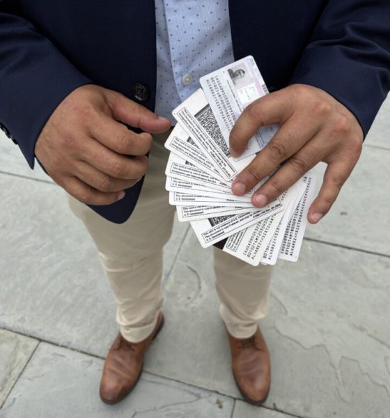 A person holding multiple identification cards in their hands, standing on a stone surface. — TPS El Salvador Expiration