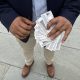 A person holding multiple identification cards in their hands, standing on a stone surface. — TPS El Salvador Expiration