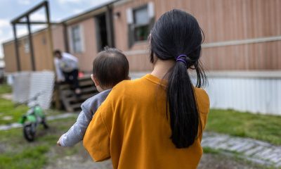 A woman holding a baby walks towards a mobile home, highlighting concerns over the new public charge rule.