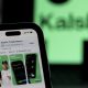 Utah sues Kalshi as a phone displays the Kalshi app listing in front of a blurred green Kalshi sign.