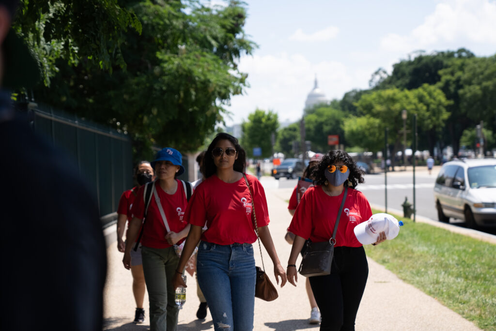 AAPI women walk together along a sunny Washington, D.C., sidewalk, carrying bags and wear — AAPI Women Reproductive Health