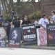 Criminal charges during pregnancy debate reflected in a sidewalk protest, with people holding anti-abortion signs and feta…