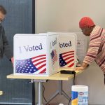 Two people use private voting booths decorated with “I Voted” signs and American f — noncitizen voting ballot measures