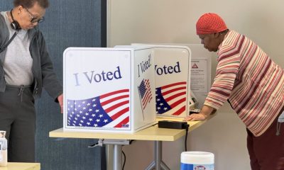 Two people use private voting booths decorated with “I Voted” signs and American f — noncitizen voting ballot measures