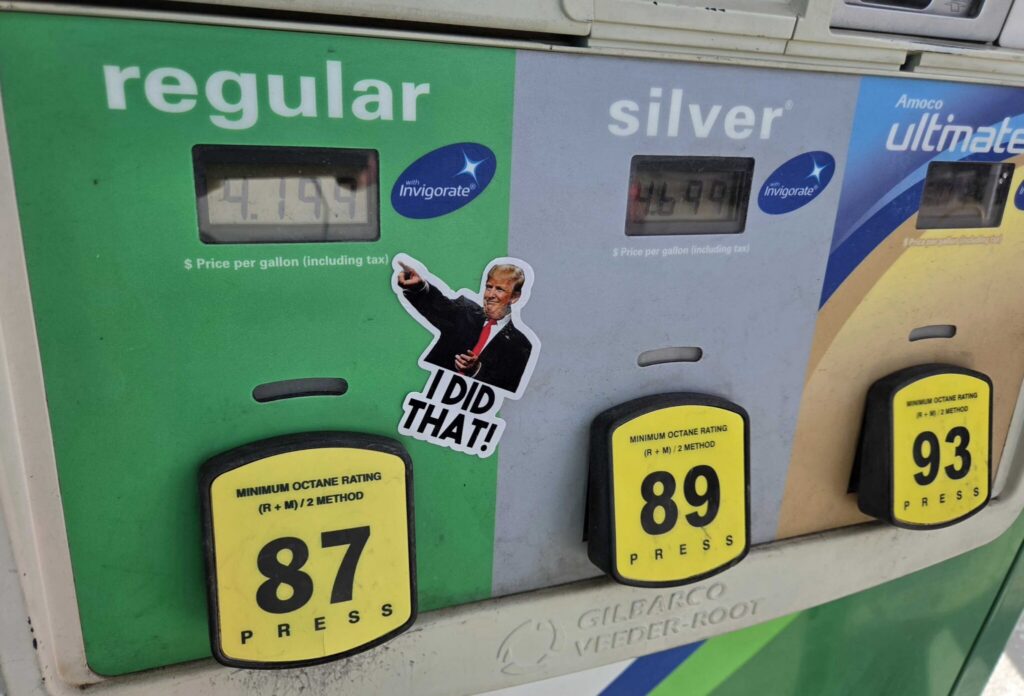 Gas pump showing fuel prices with a sticker of a man pointing and saying 'I DID THAT!' — states suspending gas tax