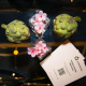 Artichokes, pink blossoms, and an Artichoke Credit Union business card arranged on a reflective table