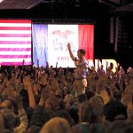 A crowd raises their hands in response to a speaker at a political rally with Am — Democrats majority of governors offices