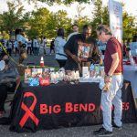 A community event with a table displaying HIV prevention materials and a man interacting w — federal HIV prevention grants