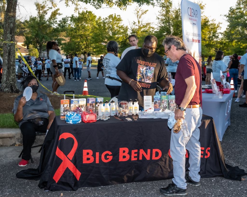 A community event with a table displaying HIV prevention materials and a man interacting w — federal HIV prevention grants