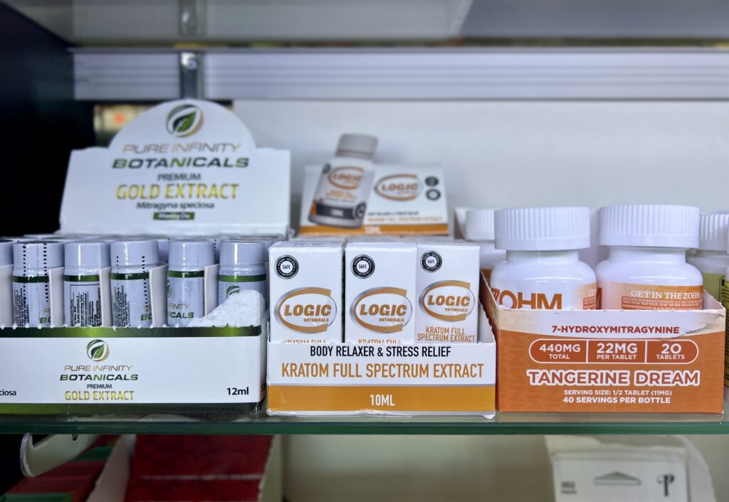 Display of kratom products including extracts and capsules on a store shelf, highlighting kratom and 7-OH laws.