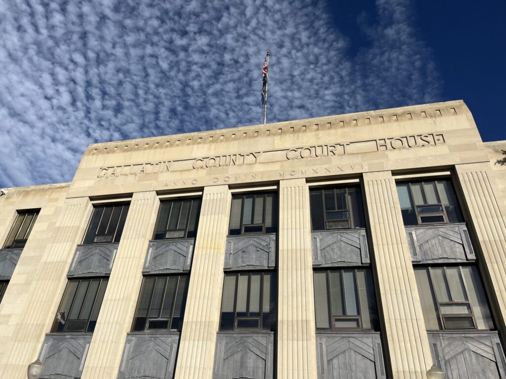 Facade of a county courthouse with a cloudy sky above, symbolizing justice — district attorney elections prison admissions
