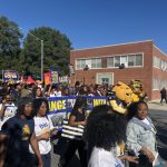 College Student Voting Access rally with students carrying voter signs and university mascots marching along a campus street