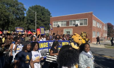 College Student Voting Access rally with students carrying voter signs and university mascots marching along a campus street