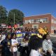 College Student Voting Access rally with students carrying voter signs and university mascots marching along a campus street