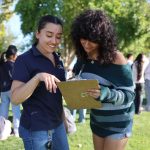Two young women discussing and taking notes outdoors, surrounded by a group of people in — Gen Z abortion ballot measures