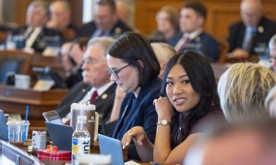 A diverse group of lawmakers in a legislative chamber, with a focus on a young woman smiling at the ca — Gen Z politicians