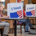 Voters cast ballots at private booths marked “I Voted,” illustrating Ballot Measure Readability concerns.