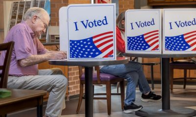 Voters cast ballots at private booths marked “I Voted,” illustrating Ballot Measure Readability concerns.