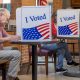 Voters cast ballots at private booths marked “I Voted,” illustrating Ballot Measure Readability concerns.