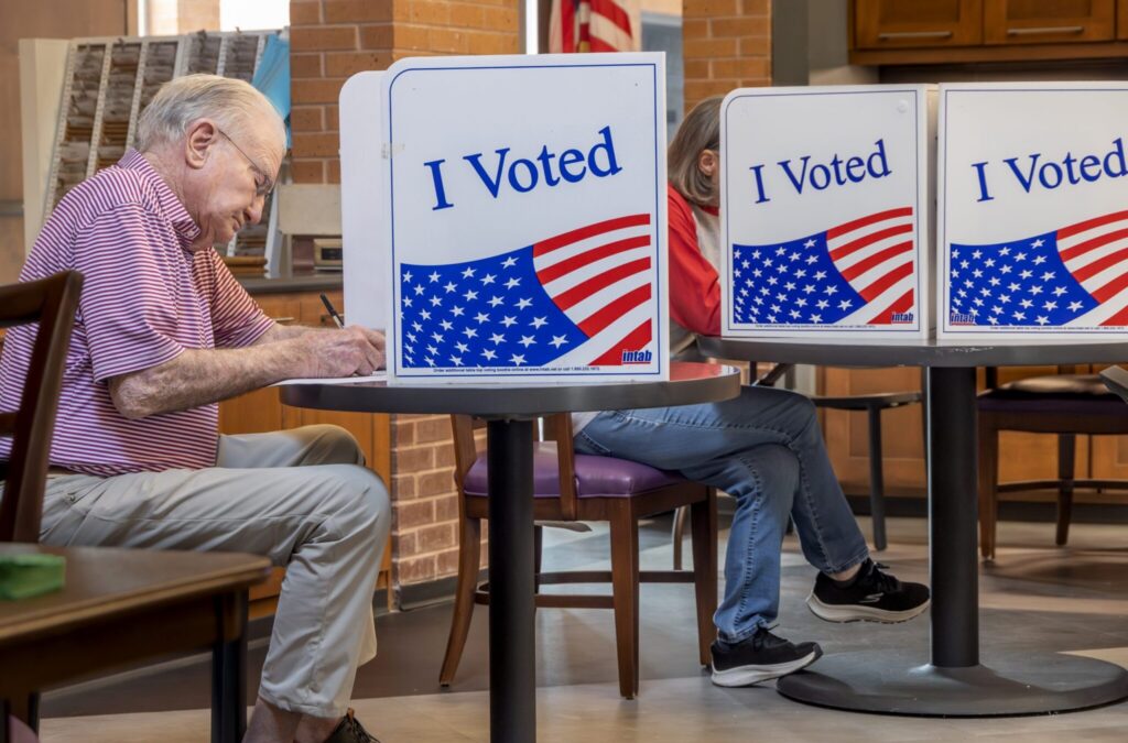 Voters cast ballots at private booths marked “I Voted,” illustrating Ballot Measure Readability concerns.