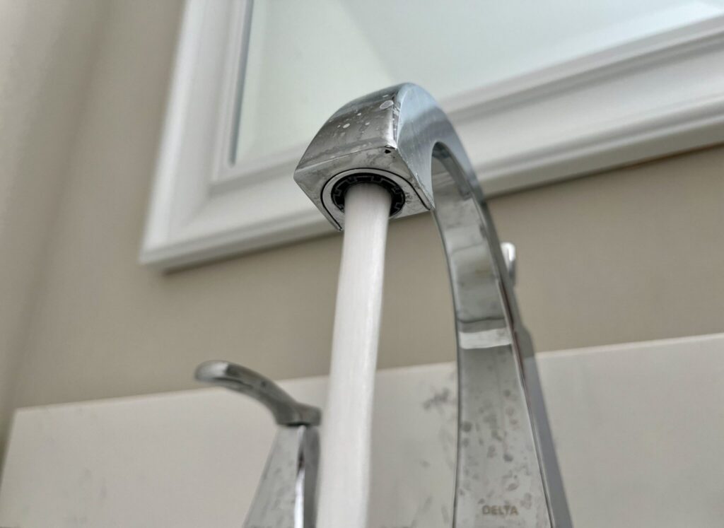 Close-up of a kitchen faucet with water flowing, highlighting rising household water bills.