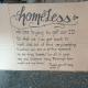 A cardboard sign reading about the struggle to obtain ID and gratitude for help, placed i — NYC Homeless Encampment Sweeps