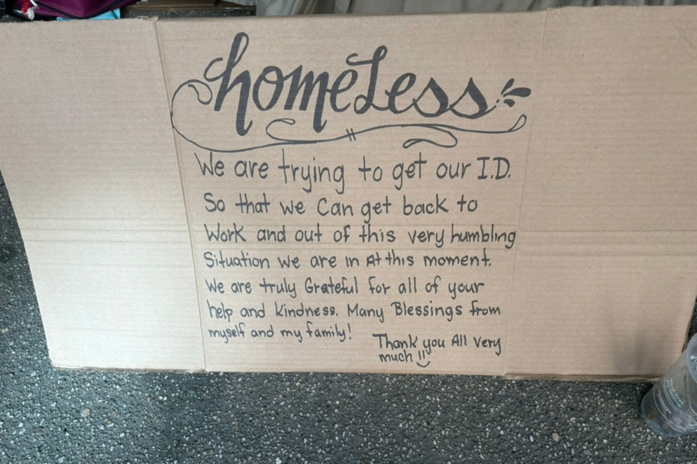 A cardboard sign reading about the struggle to obtain ID and gratitude for help, placed i — NYC Homeless Encampment Sweeps