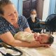 A woman cradles a newborn beside a masked caregiver; Vermont birth centers are the story context.