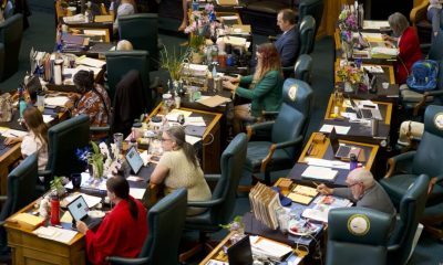 Women running for state legislature are reflected in an overhead view of lawmakers working at desks in a chamber.