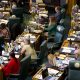 Women running for state legislature are reflected in an overhead view of lawmakers working at desks in a chamber.