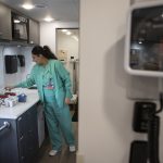 A healthcare worker in teal scrubs prepares supplies in a clinic as the uninsured rate rises. — uninsured rate rising