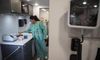 A healthcare worker in teal scrubs prepares supplies in a clinic as the uninsured rate rises. — uninsured rate rising
